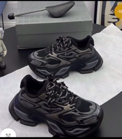 A pair of black chunky sneakers with white accents and laces on a black table, exuding luxury and sophistication.