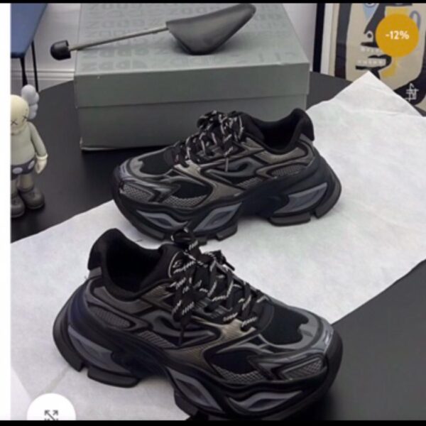 A pair of black chunky sneakers with white accents and laces on a black table, exuding luxury and sophistication.