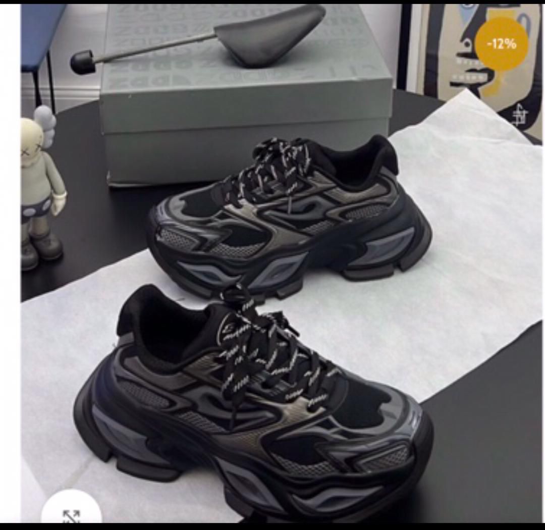 IMG-20260425-WA0012 A pair of black chunky sneakers with white accents and laces on a black table, exuding luxury and sophistication.