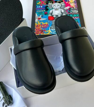 A pair of black rubber slide sandals with thick straps, displayed on a white background with a box and accessories.