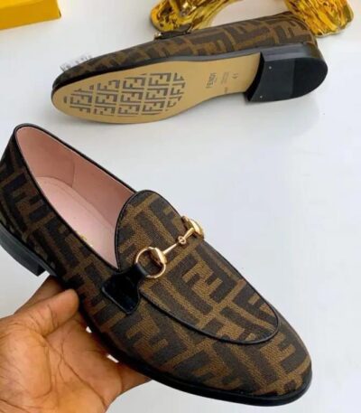 A pair of luxurious Fendi brown leather loafers with gold buckle, showcasing the shoe's intricate design and premium materials.