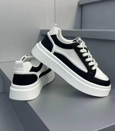 A pair of black and white sneakers with thick, white soles and laces, exuding luxury and style.