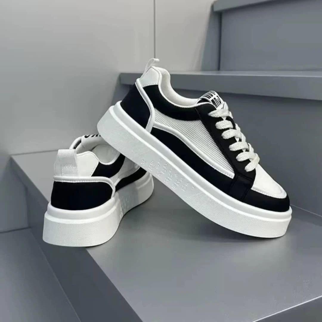 IMG-20260425-WA0028 A pair of black and white sneakers with thick, white soles and laces, exuding luxury and style.