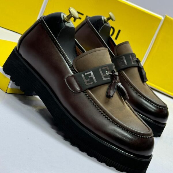 A pair of luxurious brown leather loafers with tassel details, set against a backdrop of yellow shoe boxes and a sleek alarm clock.