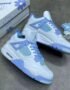 A pair of white and blue floral Air Jordan 4 Retro sneakers, accompanied by a matching box and accessories.