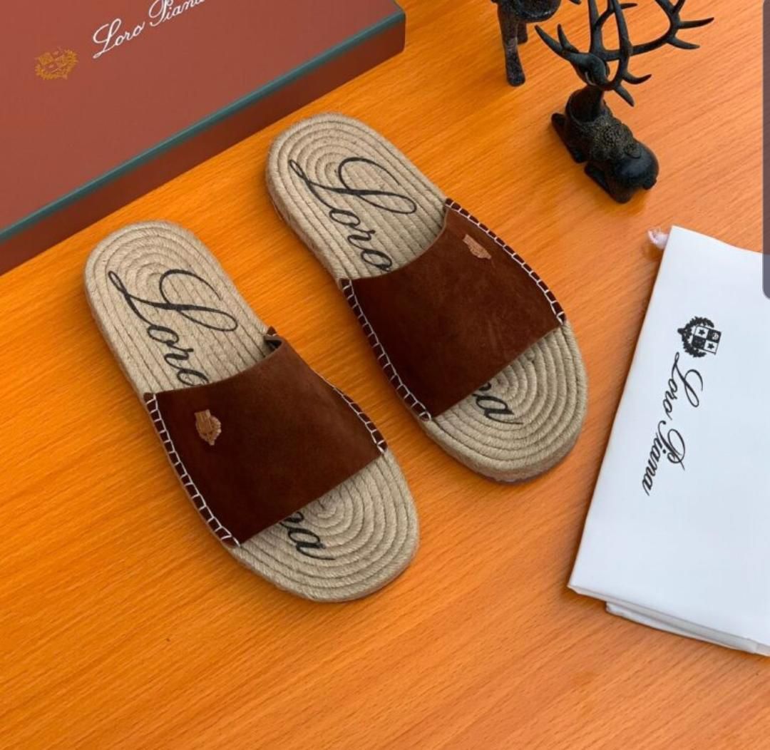 IMG-20260425-WA0043 A pair of luxurious brown leather slide sandals with jute soles and Loro Piana branding on a wooden table with packaging and accessories.