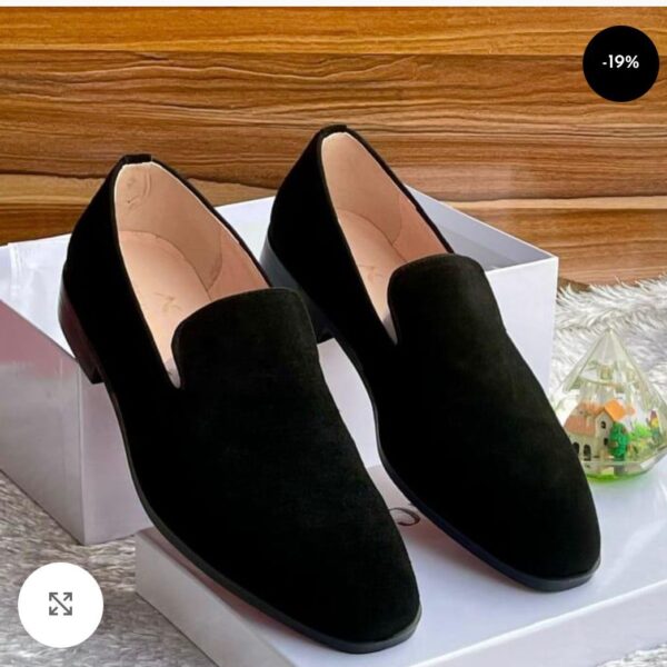 A pair of black suede loafers on a white shoe box, showcasing luxurious comfort and style.