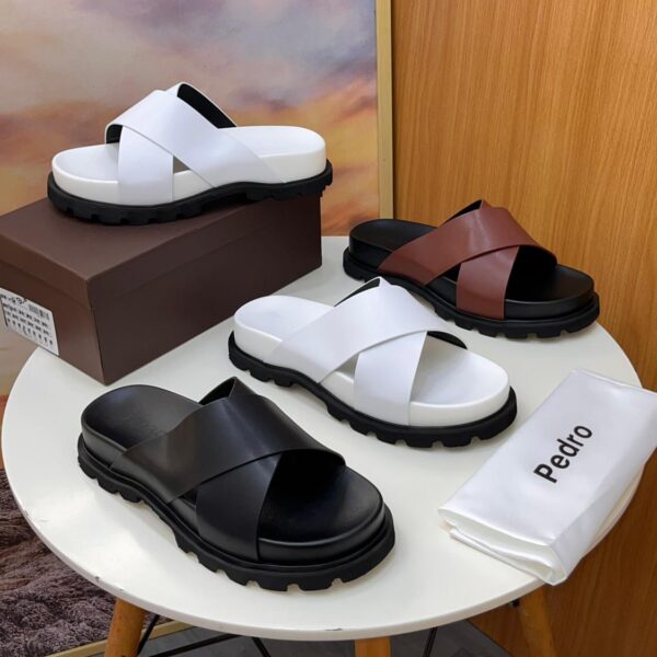 A display of Pedro two-strap leather slide sandals in black, white, and brown on a stylish table setting, showcasing their sleek design and luxurious appeal.
