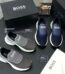 A display of Hugo Boss men's slip-on sneakers in navy blue and grey, accompanied by their original boxes and packaging.