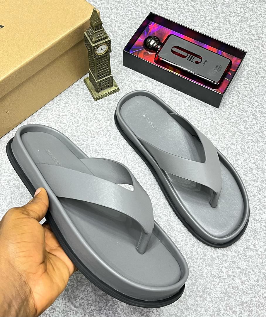 IMG-20260425-WA0057 A pair of gray rubber flip flops, a symbol of luxury and comfort, displayed on a stylish background with a touch of elegance.