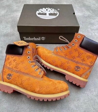 A pair of yellow leather boots with Louis Vuitton monogram pattern and Timberland box, showcasing a unique fusion of high-end fashion and rugged style.