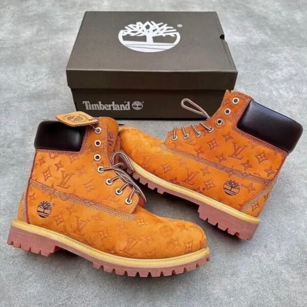 A pair of yellow leather boots with Louis Vuitton monogram pattern and Timberland box, showcasing a unique fusion of high-end fashion and rugged style.