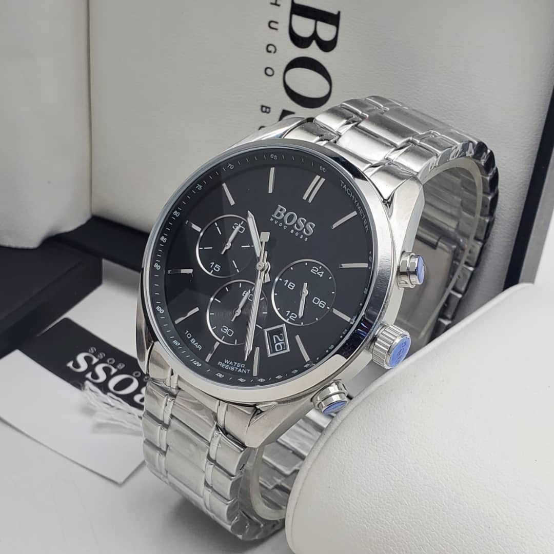 IMG-20260612-WA0004 A close-up view of a Hugo Boss men's watch with a silver-toned stainless steel band and black dial, displayed on a white surface with the brand's packaging in the background.