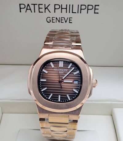 A rose gold Patek Philippe Nautilus watch with a brown dial, displayed in a white box, showcasing its sleek design and luxurious appeal.