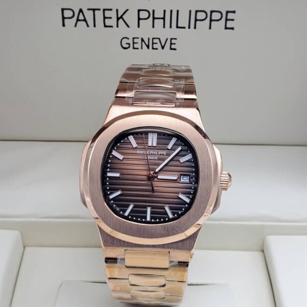 A rose gold Patek Philippe Nautilus watch with a brown dial, displayed in a white box, showcasing its sleek design and luxurious appeal.
