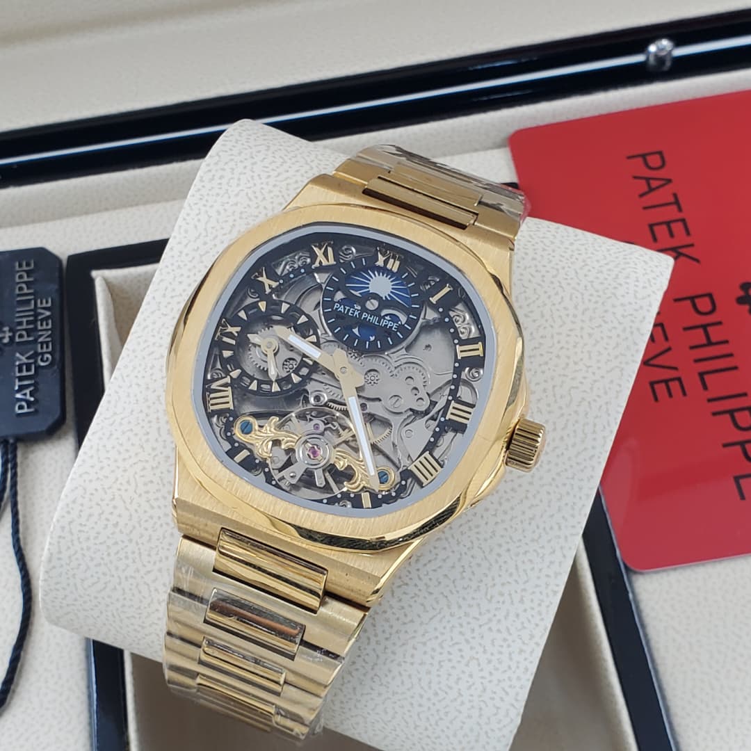 IMG-20260612-WA0017 A gold Patek Philippe Geneve Skeleton watch on a white display, showcasing its intricate mechanical details and luxurious design.