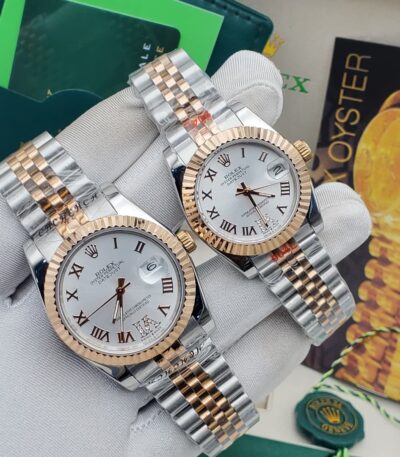 A pair of luxurious Rolex watches with white dials and two-tone stainless steel and gold bands, held in a gloved hand.