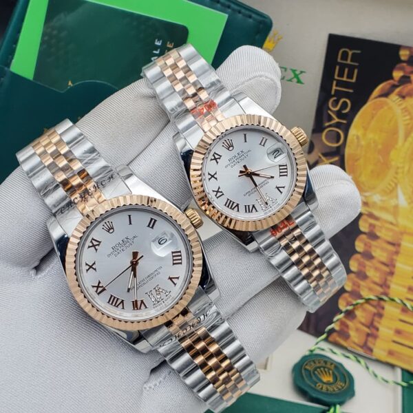 A pair of luxurious Rolex watches with white dials and two-tone stainless steel and gold bands, held in a gloved hand.