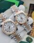 A pair of luxurious Rolex watches with white dials and two-tone stainless steel and gold bands, held in a gloved hand.