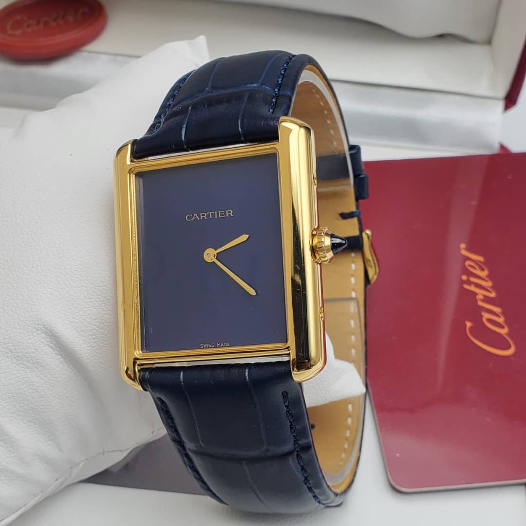 IMG-20260612-WA0024 A luxurious Cartier Tank watch with a navy blue dial and gold accents, paired with a sleek leather strap, exuding high-end style and sophistication.