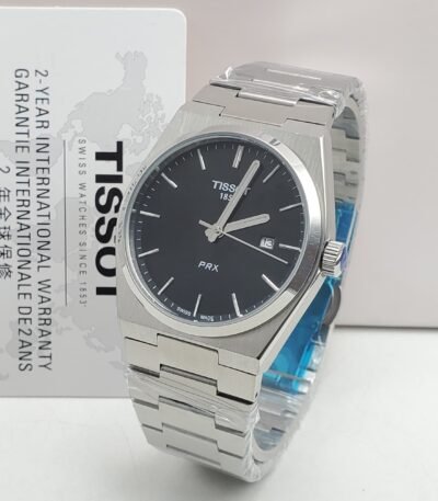 A sleek Tissot PRX watch with a black face and silver metal band, presented with its warranty card.