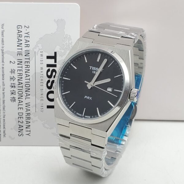 A sleek Tissot PRX watch with a black face and silver metal band, presented with its warranty card.