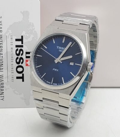 A sleek Tissot PRX watch with a blue face and silver metal band, presented with a 2-year international warranty card.