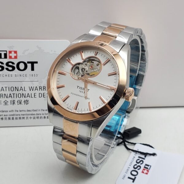 Tissot luxury watch with silver and rose gold band and white face, displayed on a white surface with its box and tag.