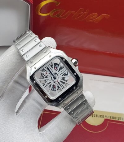 A luxurious silver Cartier watch with a sleek design and exposed mechanical components, presented on a white-gloved hand with the iconic red Cartier box in the background.