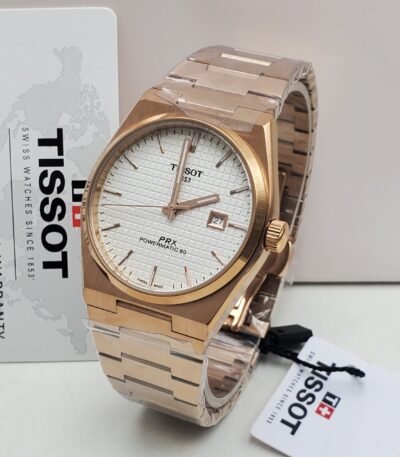 A luxurious Tissot PRX Powermatic 80 watch with a rose gold band and white face, displayed with its warranty card and packaging.