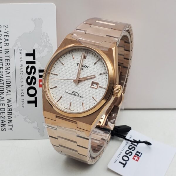 A luxurious Tissot PRX Powermatic 80 watch with a rose gold band and white face, displayed with its warranty card and packaging.