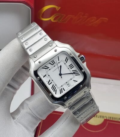 A luxurious Cartier watch with a silver band and white face, featuring Roman numerals, held by a gloved hand in front of a red Cartier box.