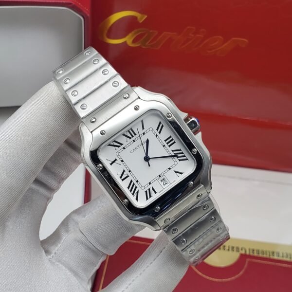 A luxurious Cartier watch with a silver band and white face, featuring Roman numerals, held by a gloved hand in front of a red Cartier box.