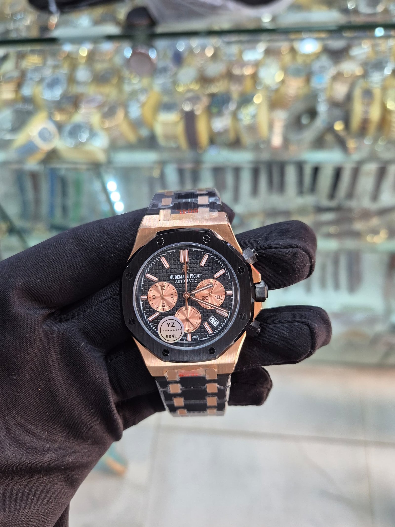 root A luxurious watch with a black and rose gold design, held by a gloved hand, showcasing its intricate details and precision.