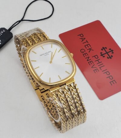 A luxurious Patek Philippe watch with a gold band and white face, accompanied by a red card and black tag, showcasing its high-end craftsmanship.