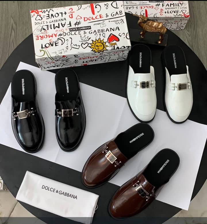 WhatsApp Image 2026-09-20 at 10.58.21 AM A stylish display of Dolce & Gabbana mule loafers in black, brown, and white, accompanied by their signature box and dust bag.